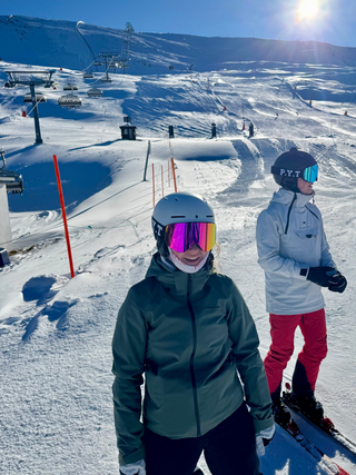 Two skiers on a snowy slope with a clear blue sky