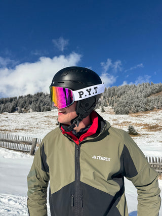 Person wearing a ski helmet and goggles with a snowy landscape in the background